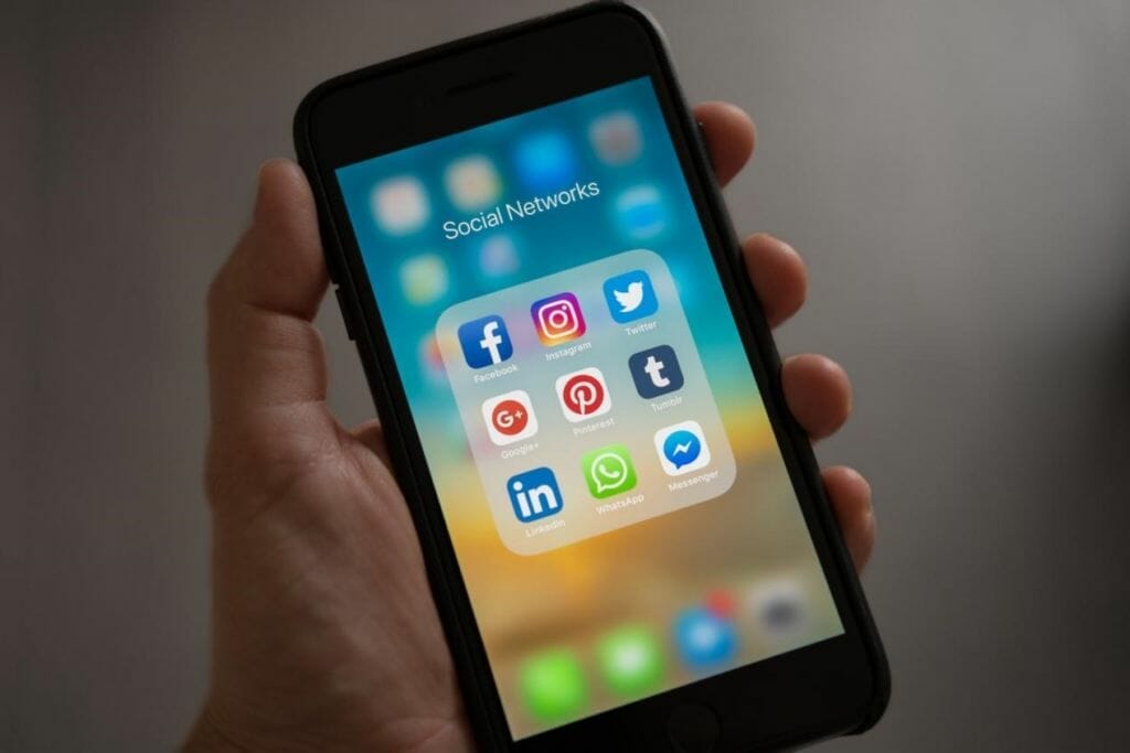Hand holding an iphone with social networking apps on the screen