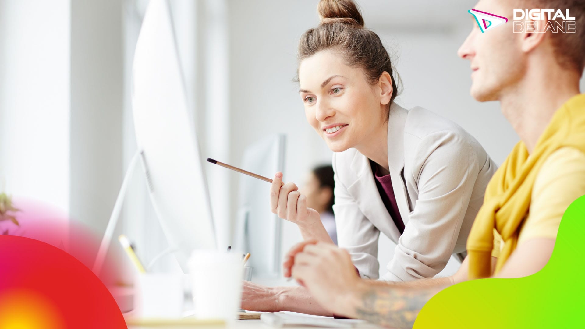 A woman and a man collaborate on a computer, focused on their work and sharing ideas in a professional setting.