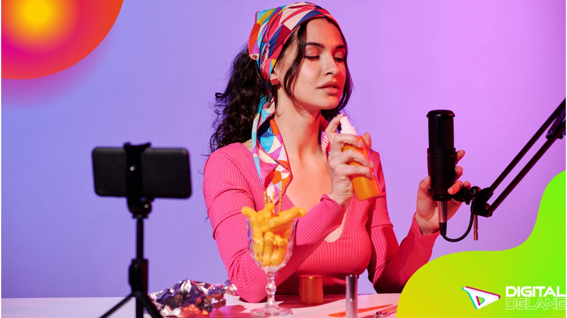 A woman at a table with a microphone and a drink, poised to engage her audience in a creative discussion.