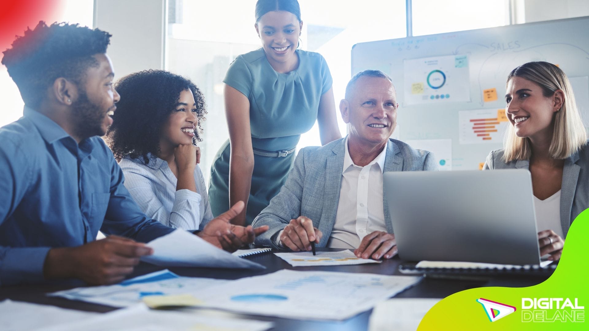 A diverse group of business professionals collaborates at a table, discussing digital marketing strategies and solutions.