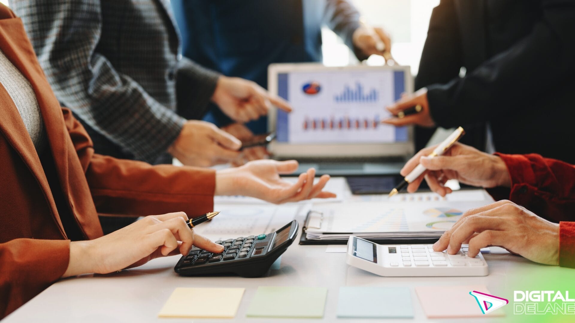Business professionals collaborating on a laptop, utilizing a calculator and papers to analyze social selling metrics and strategies.