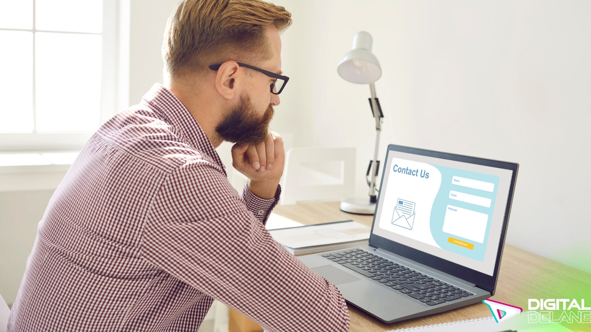 A man seated at a desk, focused on his laptop computer, engaged in work or study.