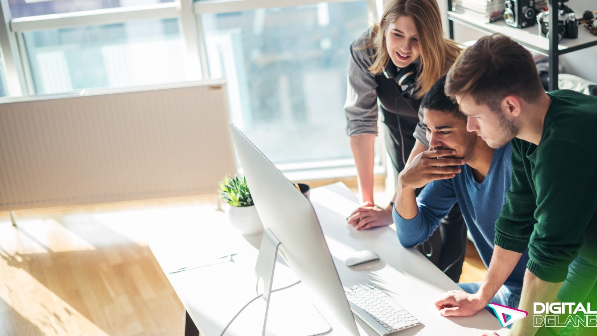 Three individuals collaborating on a computer in an office setting, focused on web design and accessibility solutions.