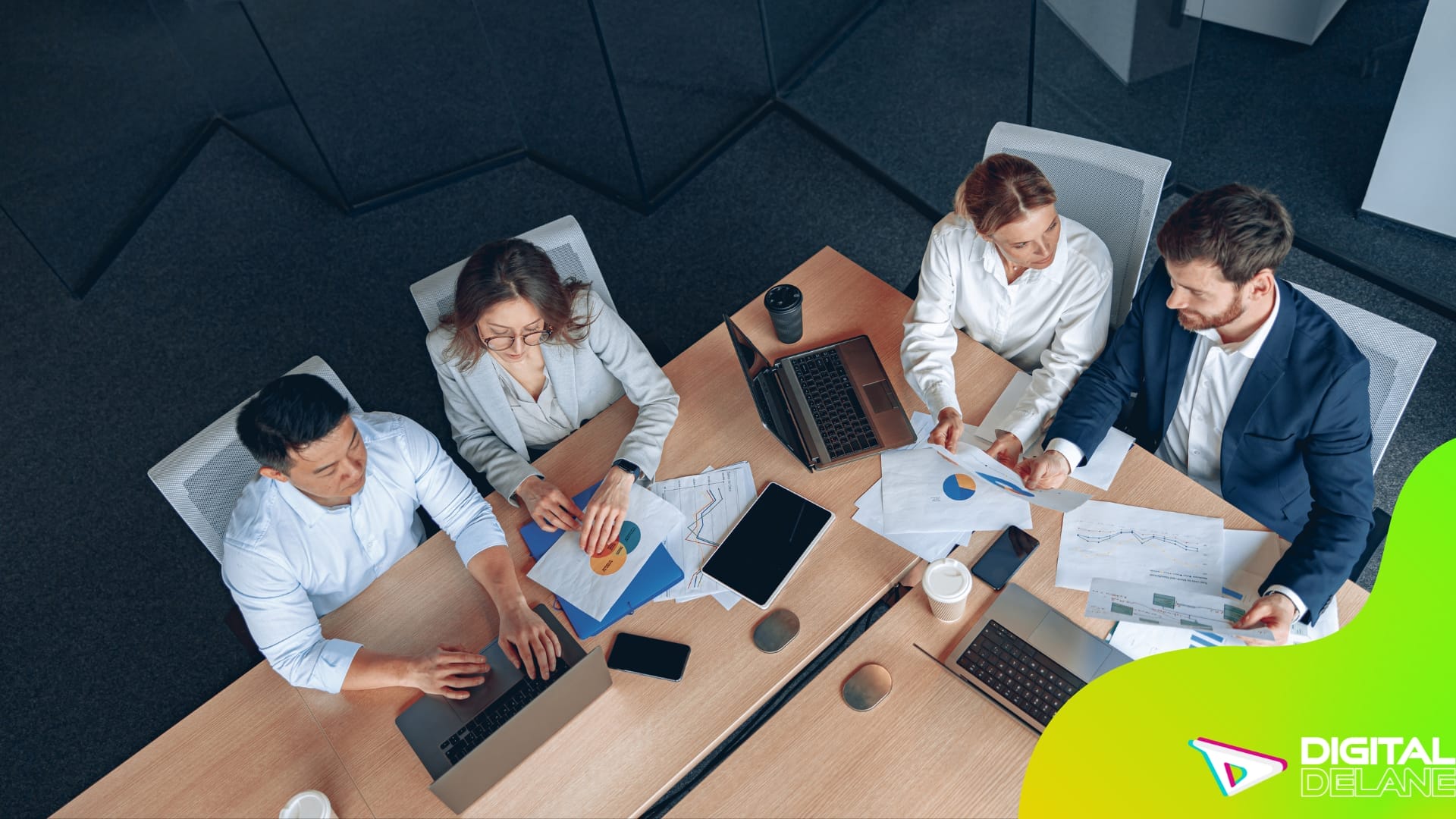 A diverse group of individuals collaborating around a table, each engaged with their laptops in a productive environment.