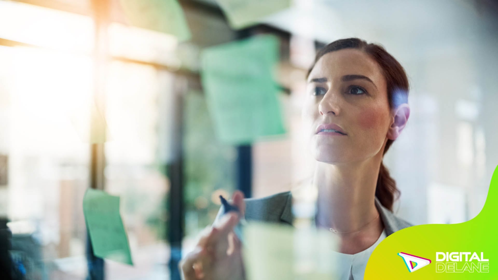 A woman examines colorful sticky notes affixed to a glass wall, contemplating ideas for enhancing customer experience.