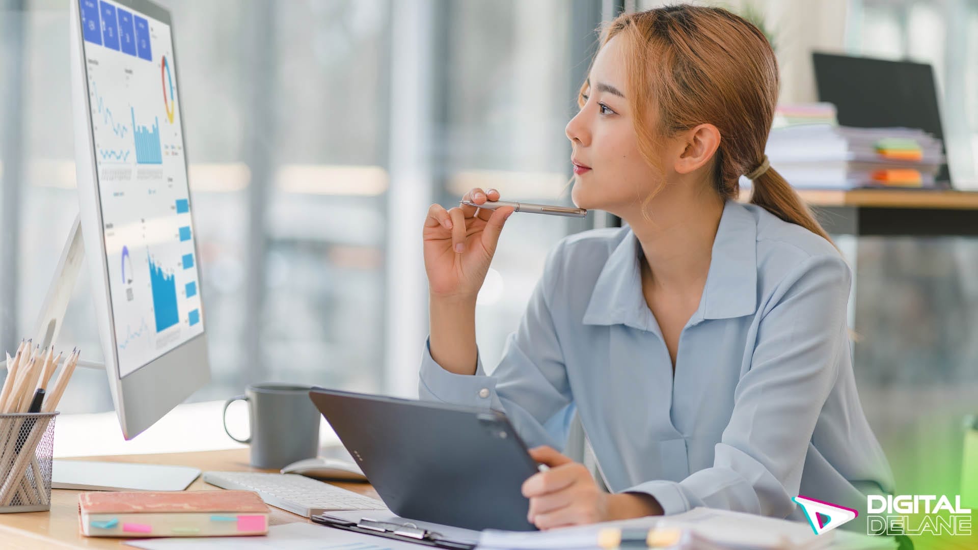 A woman at a desk using a laptop and pen, focused on analyzing data to enhance customer journey mapping strategies.
