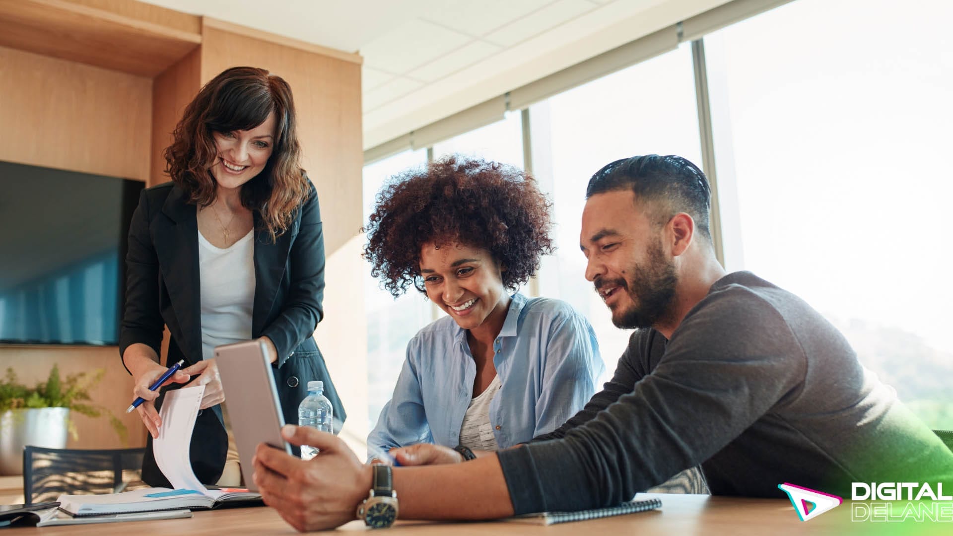 Three individuals collaborating at a table, utilizing a laptop for a business discussion or project planning.