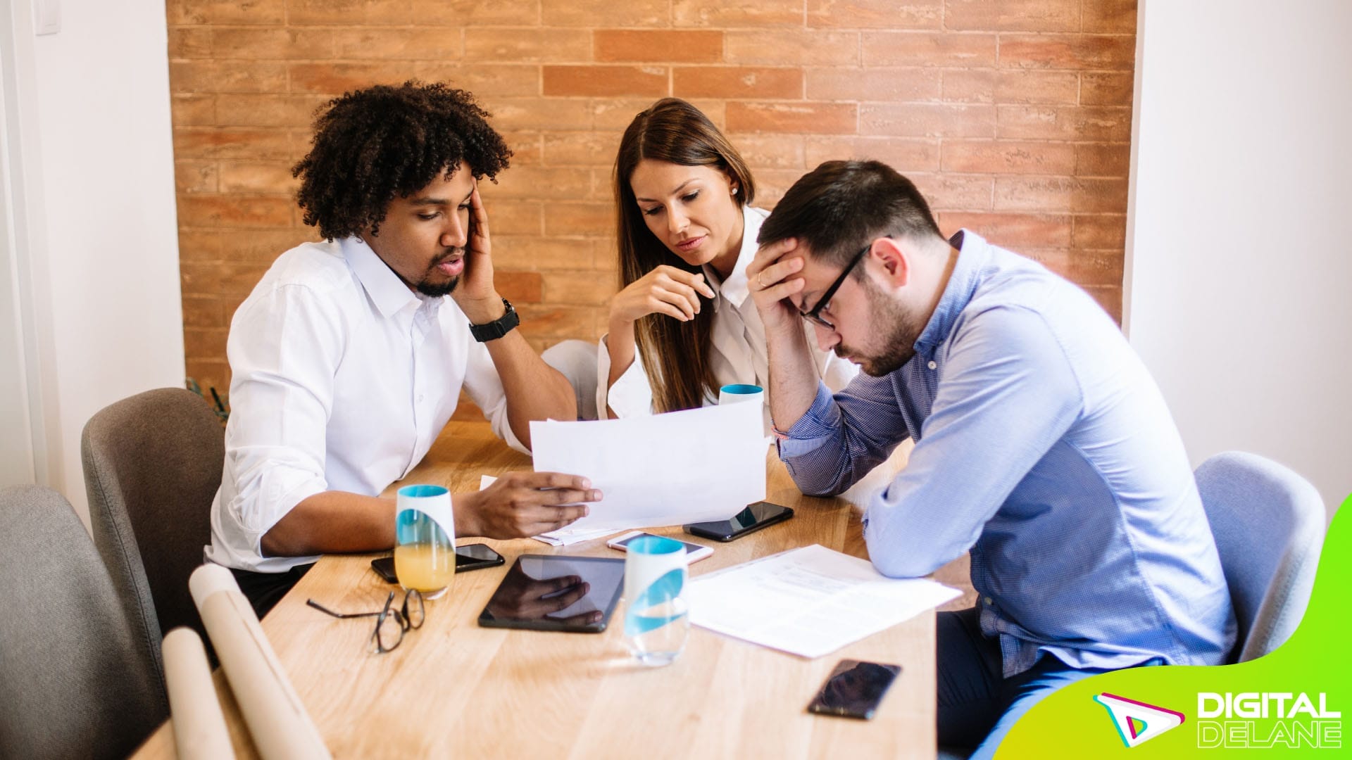 Three individuals seated at a table, examining a document together, engaged in discussion or planning.